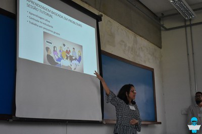 Foto de uma Professora, apresentando um slide sobre "Aprendizagem baseada em problemas".